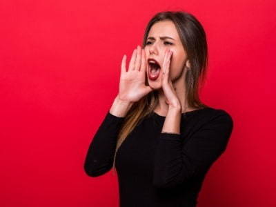 Red wall with lady holding hands up to mouth and shouting